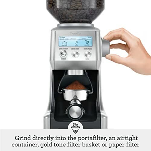 Person adjusting a coffee grinder with digital display and portafilter.