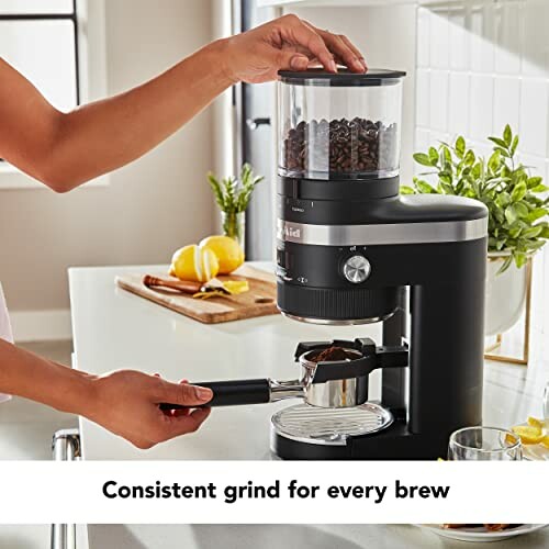 Person using a coffee grinder with fresh coffee beans in a kitchen setting.