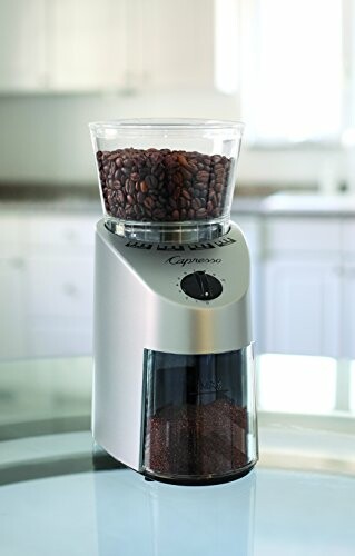 Coffee grinder with coffee beans on top and ground coffee below.