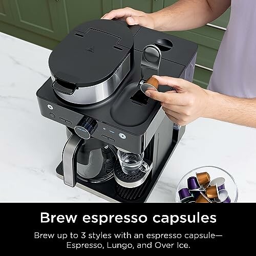 Person using an espresso capsule brewer with capsules and a carafe.