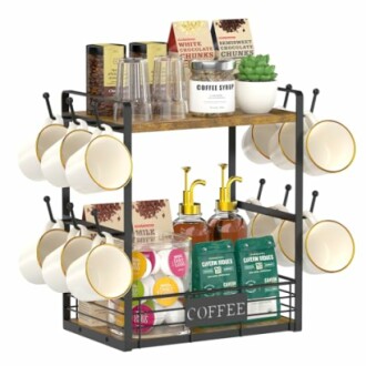 Kitchen counter coffee station organizer with mugs, coffee pods, syrups, and snacks.